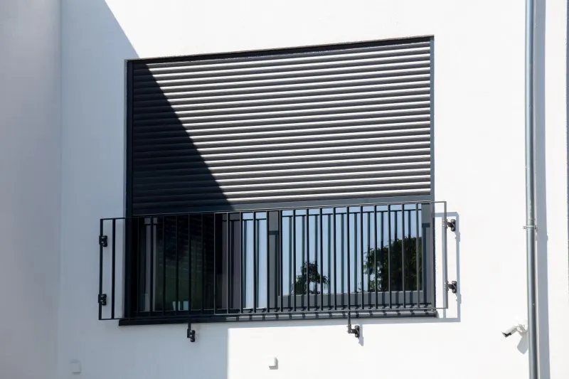 Weißer Rollladen an einer hellen Fassade